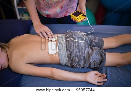 High angle view of female therapist placing electrodes on back at hospital ward