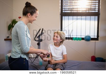 Smiling boy looking at female therapist scanning wrist at hospital ward