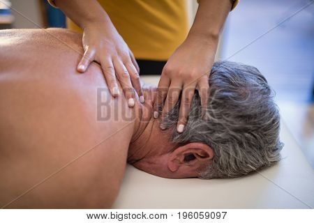 High angle view of female therapist giving neck massage to male patient at hospital ward