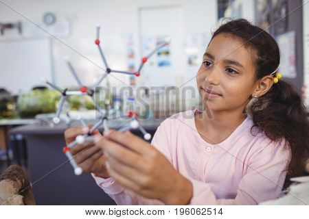 Elementary student examining molecule model at science laboratory