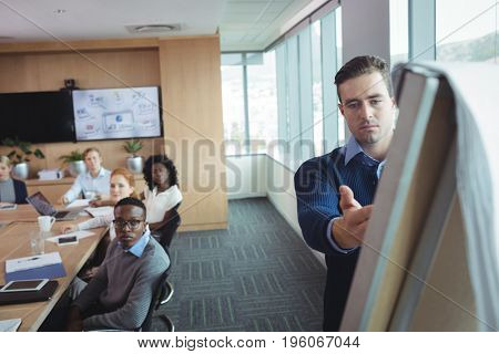 Serious businessman explaining strategy to colleagues in meeting room at office