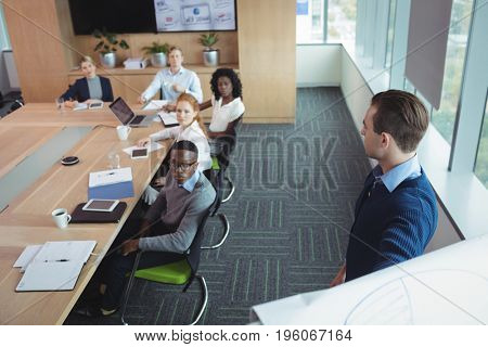 Serious business entrepreneur explaining strategy to colleagues in meeting room at office