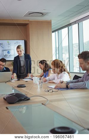 Young businesswoman with team working at conference table in meeting room