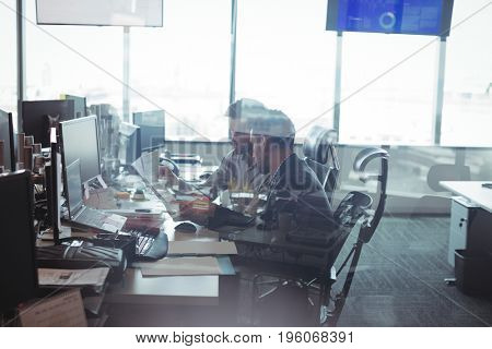 Side view of male business colleagues seen through glass working together in office