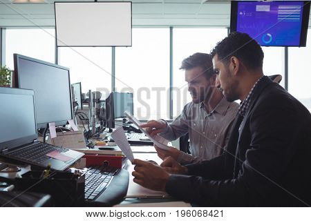 Side view of focused male business colleagues working together at desk in office