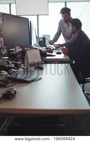 Young male business colleagues discussing over documets at desk in office
