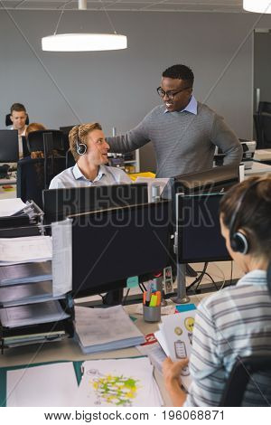 Male business colleagues dicussing at desk in office