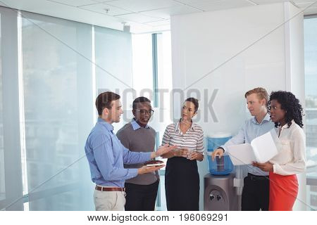 Young business partners discussing while standing at office
