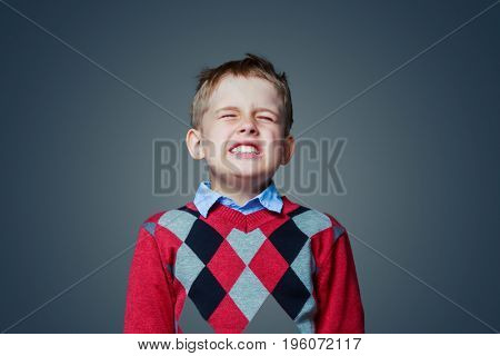 displeased child isolated against grey background