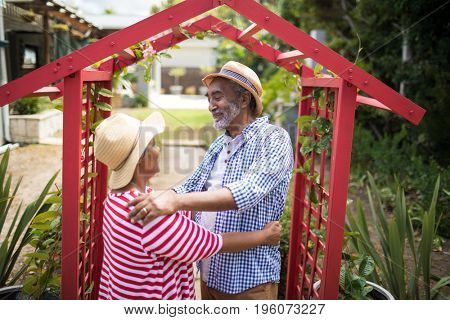 Smiling senior couple standing face to face by metallic structure in yard