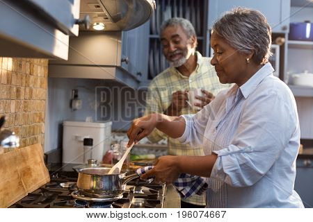 Happy senior couple preparing food while standing in kitchen at home