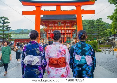 KYOTO JAPAN - NOVEMBER 24, 2016: Young tourists giving a back, visiting a fushimi inari temple at rainy day in Kyoto, Japan.