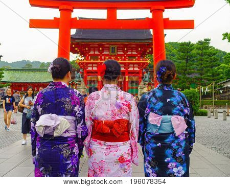 KYOTO JAPAN - NOVEMBER 24, 2016: Young tourists giving a back, visiting a fushimi inari temple at rainy day in Kyoto, Japan.