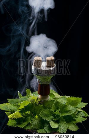 Mint smoking hookah with leafs on black background