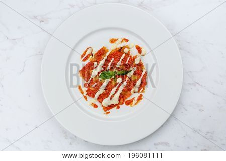 Ravioli with tomato sauce served in white plate on marble serface.