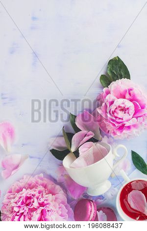 Minimal styled flatlay with pink peony flowers, petals and leaves. Top view on a light pastel background.