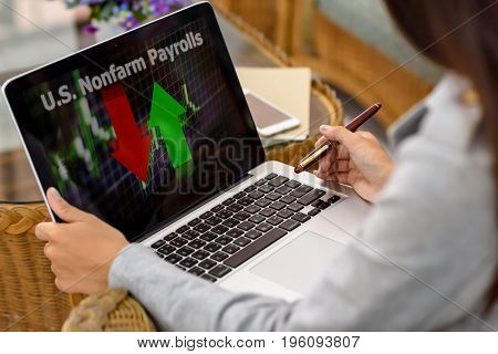 U.S. Nonfarm Payrolls word with businesswoman holding a pen looking at a laptop computer screen.