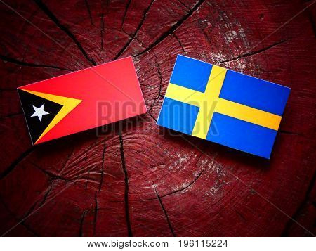 East Timorese Flag With Swedish Flag On A Tree Stump Isolated