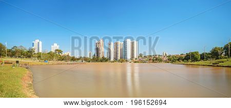 Sunny day at a lake of a park with few buildings on background a amazing clear blue sky and surrounded by nature. Photo at Parque das Nacoes Indigenas in Campo Grande city.