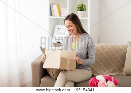 delivery, mail and people concept - smiling woman opening cardboard box at home
