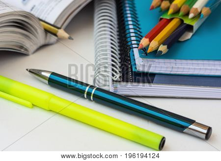 School supplies stationery multicolored pencils pen highlighter opened math workbook on white desktop learning studying college