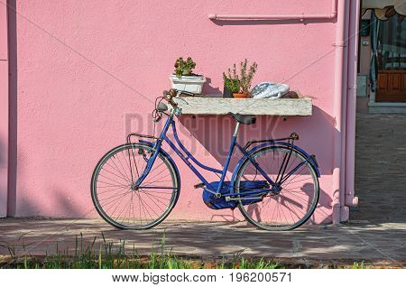 Close-up of bicycle leaning against colorful wall on a sunny day in Burano, a gracious little town full of canals, near Venice. Located in the Veneto region, northern Italy
