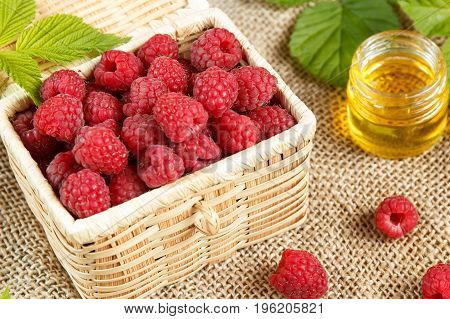 Fresh raspberries in a wicker box and honey green leaves.