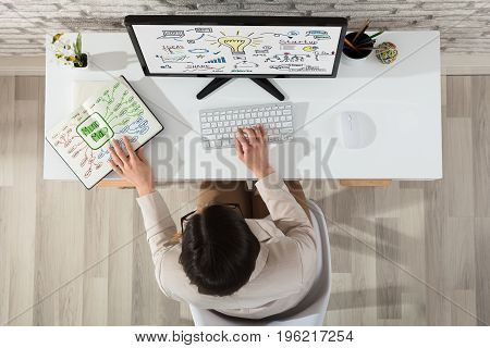 A Businesswoman Planning Start Up Plan On Computer With Mind Map Chart On Notebook