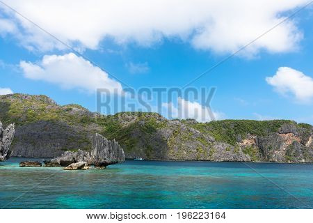 Sharp rocks with tropical vegetation in El Nido's bay during summer time. Beautiful scenic landscape in Palawan Philippines.