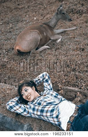 Beautiful smiling Asian woman lying down and emulate deer.