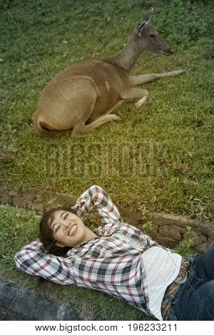 Beautiful smiling Asian woman lying down and emulate deer.