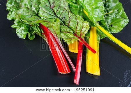 The colorful stems of Chard on dark slate, from above