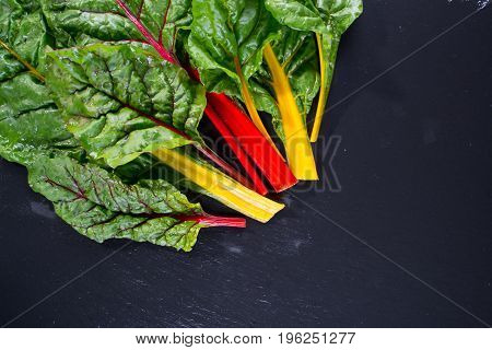 The colorful stems of Chard on dark slate, from above