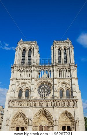 Notre Dame de Paris central main facade, national monument cathedral of France. French Gothic architecture. Sunny blue cloudy sky.