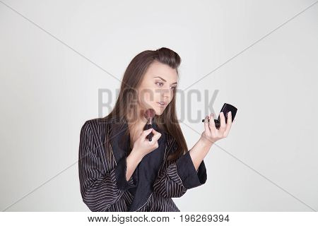 girl in coat makes brush makeup looks in the mirror 1