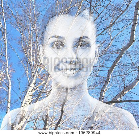 Double exposure portrait of beautiful woman combined with photograph of tree.