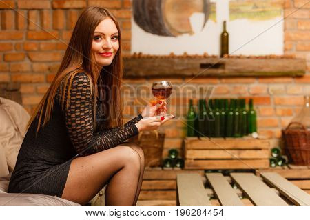 Woman Tasting Wine In Rural Cottage Interior
