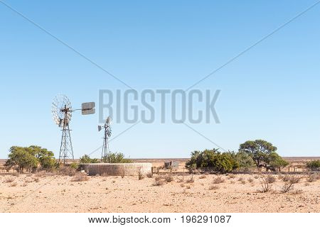 A farm scene with two windmills a dam and a hut next to the C10-road between Velloorsdrif border post and Karasburg in the southern part of Namibia