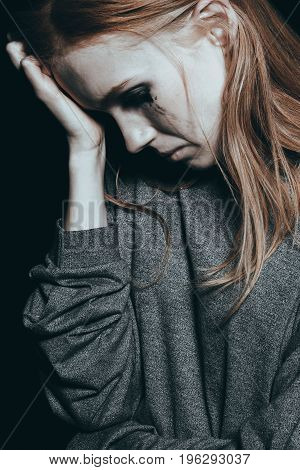 Depressed young girl in tears supporting her head on her hand