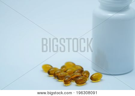 Brown soft gelatin capsule pills with closed bottle on white background