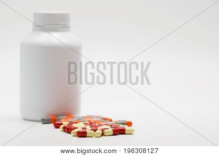 Capsule pills with closed bottle on white background