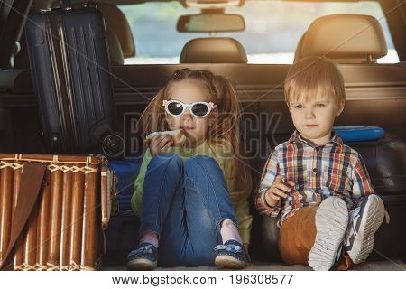 Travel by car family together brother and sister sitting in a trunk