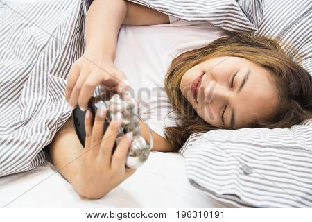 Young asian woman lying in bed watching the clock, Young woman don't want to wake up, Young woman is so broken hearted to get out of bed