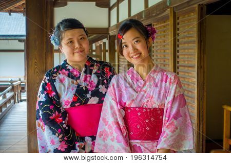 KYOTO, JAPAN - JULY 05, 2017: Close up of two beatiful Japanesse girls posing for camera in Hojo Hall of Tenryu-ji in the Arashiyama district of Kyoto, Japan.