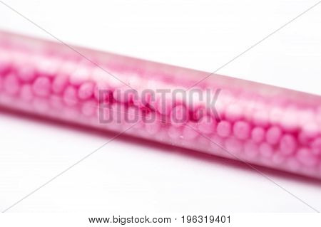 Drinking straws on white background with copy space. Top view of pink eco-friendly straws wiht strawberry balls for summer cocktails.