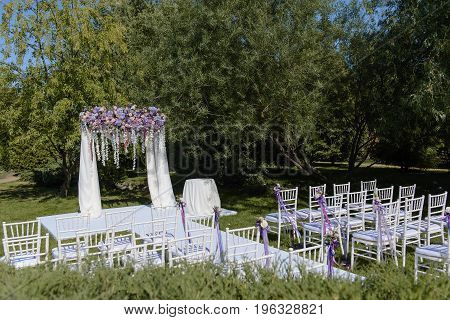 Wedding ceremony in white, violet, blue, pink colors outdoors in wide format