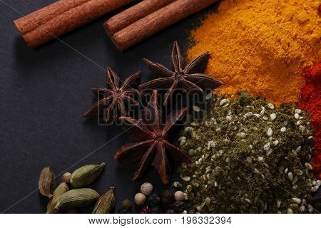 Spices scattered on a black background shot from above
