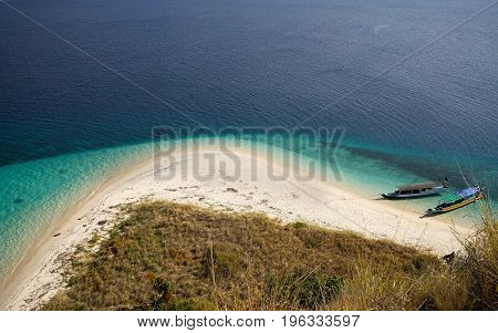 Top View Of Two Boats At The Coast Of A White Sand Beach Surrounded By  Blue Turquoise Colored Ocean