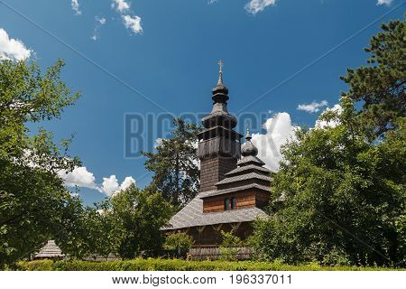 Old wooden Lemk church against a bright blue sky with clouds. Culture of Ukraine
