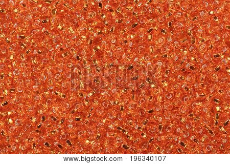 Multicolored orange seed beads background. High resolution photo.